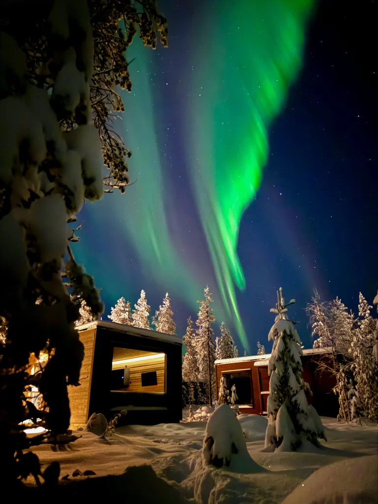 Aurores boréales au-dessus des cabanes enneigées d'Aurora Hill Resort