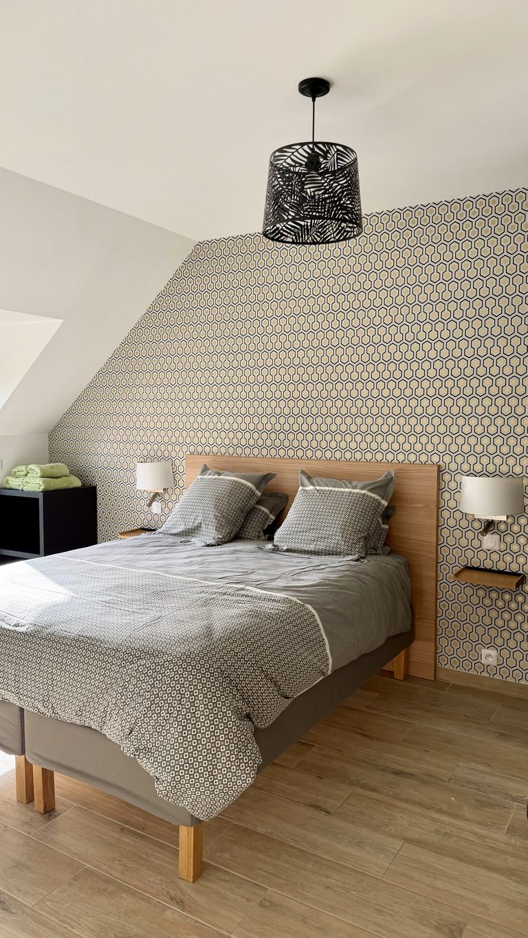 Chambre avec lit double et papier peint graphique dans le cottage Aux Bois Dorés, Ferme de Sorval