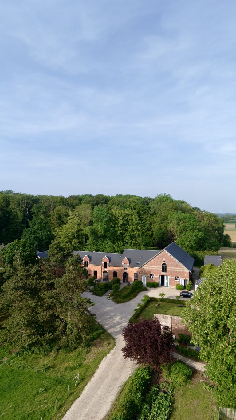 Vue aérienne du corps de ferme en briques rouges de la Ferme de Sorval entouré d'arbres