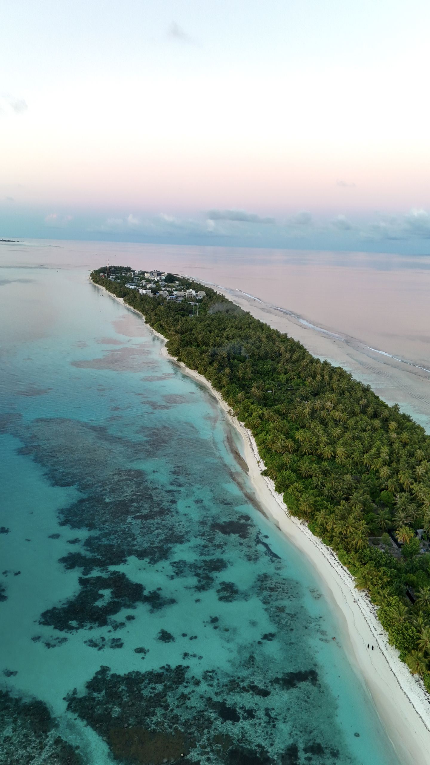 Vue au drone de l’île de Dhigurah aux Maldives, sa longue plage de sable blanc et son lagon turquoise au coucher du soleil