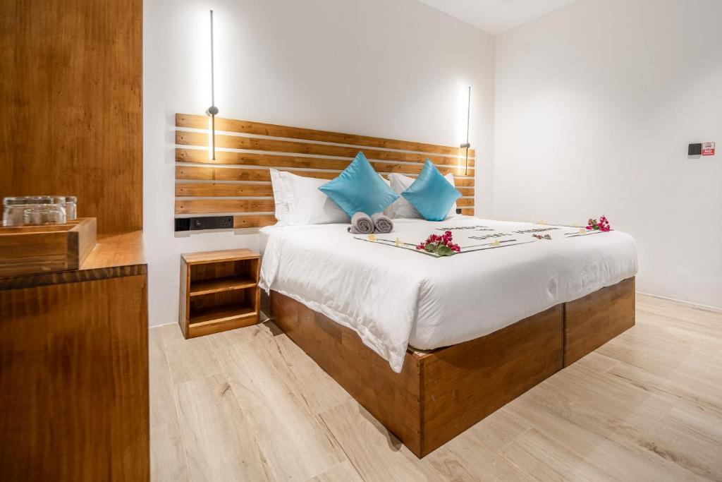 Chambre avec grand lit et décoration en bois à Oasis Dhigurah, Maldives