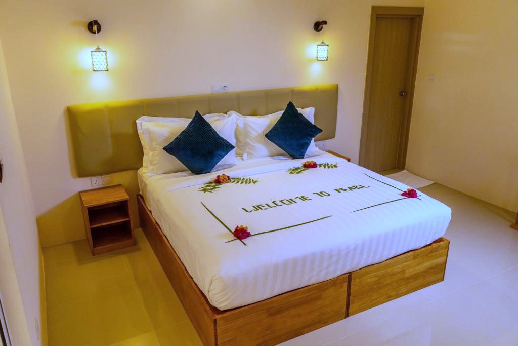 Chambre avec grand lit en bois au Pearl Dhigurah, Maldives