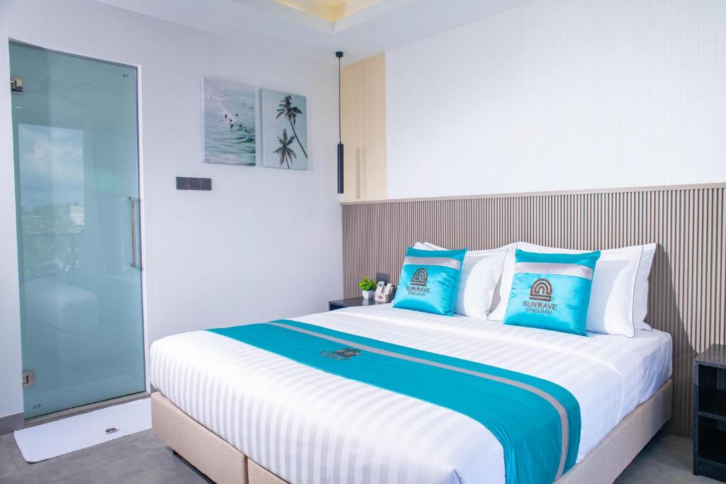 Chambre avec grand lit et coussins turquoise au Sunwave Dhigurah, Maldives