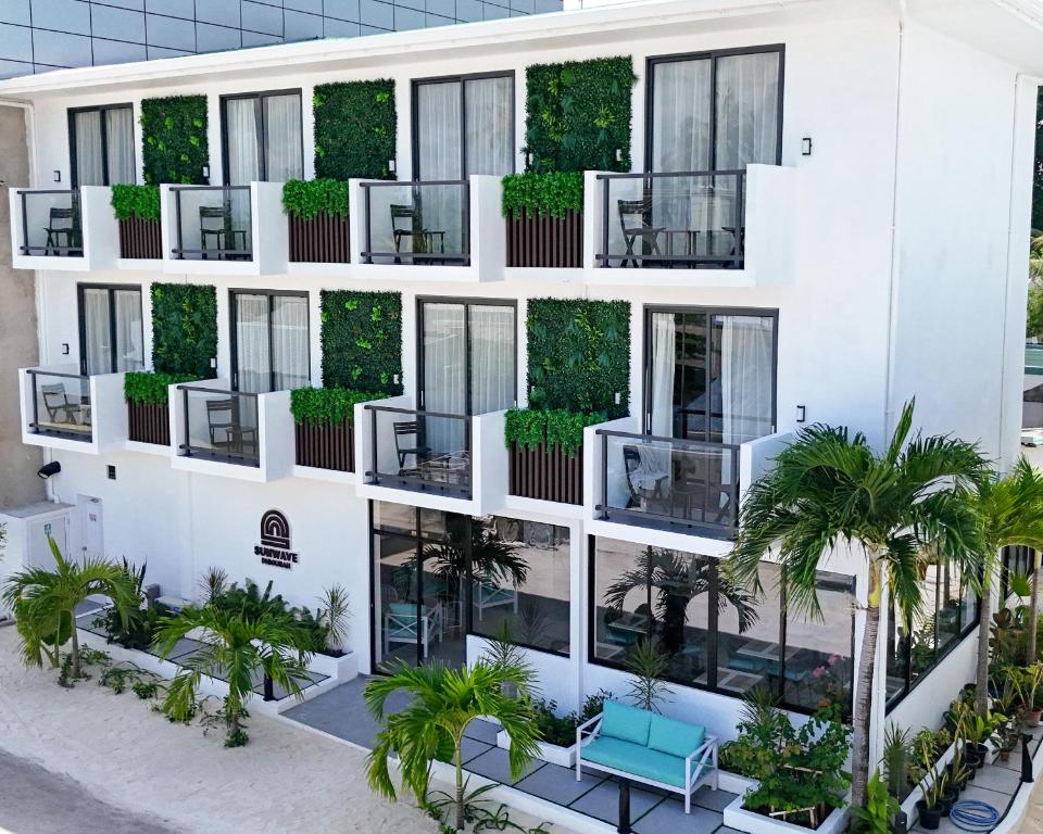 Façade blanche avec balcons et palmiers du Sunwave Dhigurah