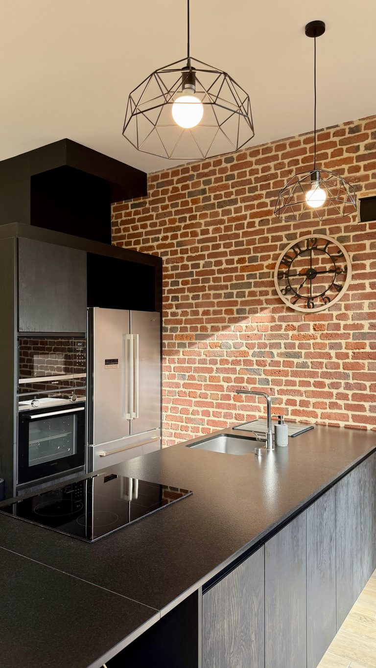 Cuisine moderne avec mur en briques du gîte de la Ferme de Sorval