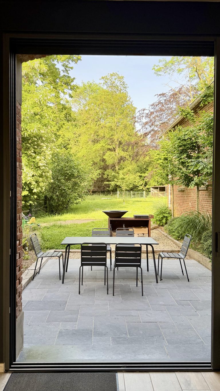 Terrasse avec table et jardin arboré du gîte de la Ferme de Sorval