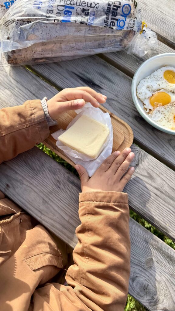 Enfant tartinant du beurre au petit-déjeuner en plein air