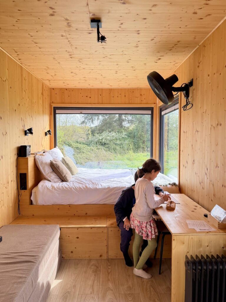 Enfants faisant leurs devoirs au bureau en bois de la mezzanine de la tiny house
