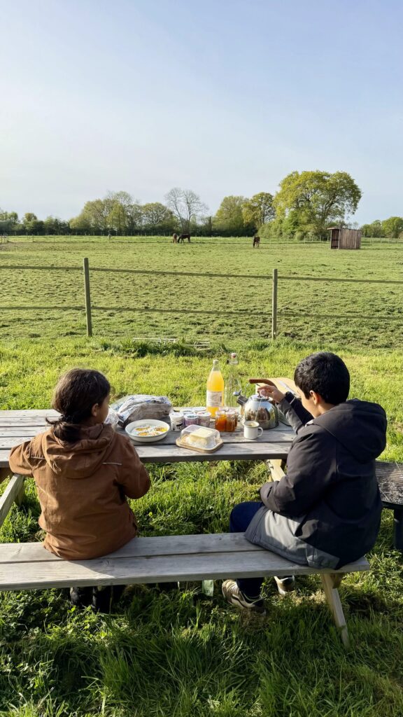 Famille prenant son petit-déjeuner en plein air face aux chevaux, séjour tiny house kids friendly