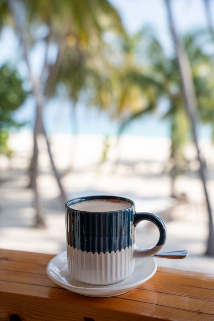 Tasse de café face à la plage bordée de palmiers à Maalhos